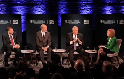 Video Production Example: a group of panelists are sitting on a stage engaged in active conversation with a moderator as an example of a successful live stream.