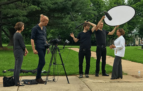 Video Production Service: Image of a video production crew filming a subject in a white lab coat outdoors on a sunny day, showcasing our team's dedication to capturing professional and visually engaging content for their client.